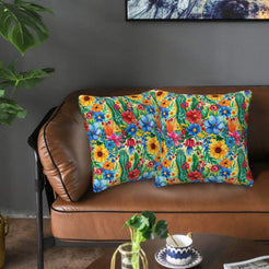 Mexican-inspired velvet pillow covers with tropical flowers and birds on yellow, styled on a brown leather sofa