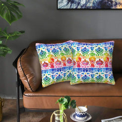 Mexican-inspired velvet pillow covers with multicolor folk floral borders, styled on a brown leather sofa