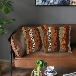 Velvet pillow covers with rust and cream wavy dot stripes, styled on a leather sofa