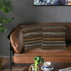 Velvet pillow covers with black and brown linear symbols, styled on a leather sofa