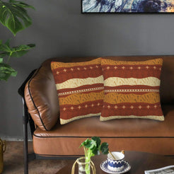 Velvet pillow covers with rust and beige horizontal geometric bands, styled on a leather sofa