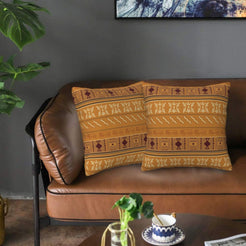 Velvet pillow covers with mustard and brown animal and geometric bands, styled on a leather sofa