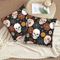 Halloween velvet pillow covers with black skulls, mushrooms, spiderwebs and flowers, styled on a woven chair