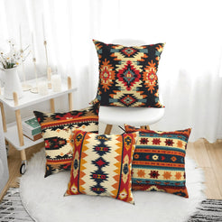 short-pile plush polyester pillow covers with black, rust and cream Aztec geometric prints, arranged beside a white chair