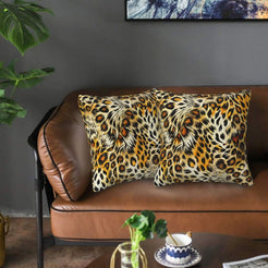 Velvet pillow covers with mixed leopard rosettes and zebra-like streaks, styled on a brown leather sofa