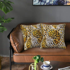 Velvet pillow covers with large golden leopard rosettes, styled on a brown leather sofa