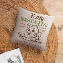Linen-look pillow cover with Kitty Biscuits cat illustration, shown in a flat lay
