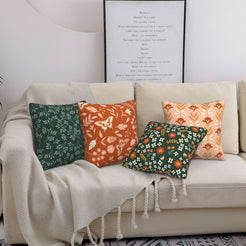 Rust and green botanical pillow covers styled on a beige sofa