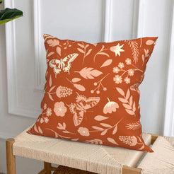 Rust botanical short-pile plush pillow cover styled on a woven chair