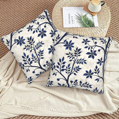 Block-print-inspired velvet pillow covers with navy flowering branches, styled on a woven chair
