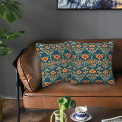 Ethnic damask velvet pillow covers with small orange flowers on deep teal, styled on a brown leather sofa