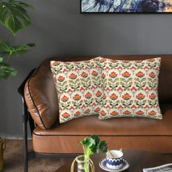 Ethnic damask velvet pillow covers with small red and yellow flowers on cream, styled on a brown leather sofa