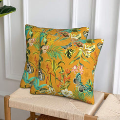 Velvet pillow covers with birds, butterflies and flowers on mustard, styled on a woven chair