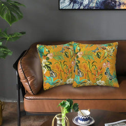 Velvet pillow covers with birds, butterflies and flowers on mustard, styled on a brown leather sofa