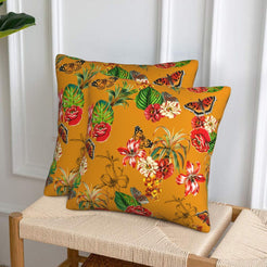 Velvet pillow covers with red flowers and butterflies on mustard, styled on a woven chair