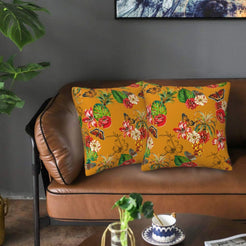 Velvet pillow covers with red flowers and butterflies on mustard, styled on a brown leather sofa