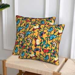 Velvet pillow covers with bright butterflies and leaves on mustard, styled on a woven chair