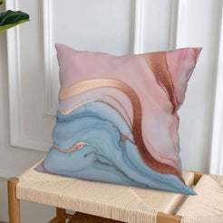 Short-pile plush pillow cover with blush, blue and rose gold marble designs, styled on a woven chair