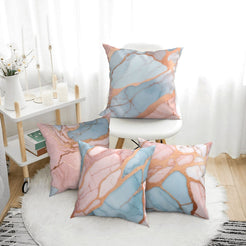 Four short-pile plush pillow covers with peach, blush and blue marble designs, styled in a bright room