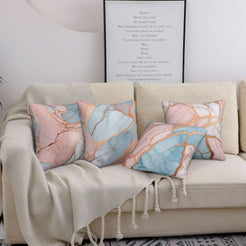 Four short-pile plush pillow covers with peach, blush and blue marble designs, styled on a sofa