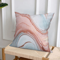 Short-pile plush pillow cover with blush, blue and gold marble designs, styled on a woven chair