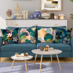 Short-pile plush pillow covers with dark tropical leaves and leopard spots, styled on a teal sofa