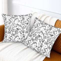 Toile floral velvet pillow covers with black birds and wildflowers on white, styled on a sofa
