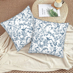 Toile floral velvet pillow covers with blue birds and wildflowers on white, styled on a woven chair
