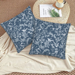 Toile floral velvet pillow covers with white birds and wildflowers on blue, styled on a woven chair