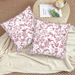 Toile floral velvet pillow covers with burgundy birds and wildflowers on white, styled on a woven chair