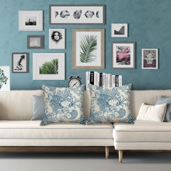 Water-resistant linen-look polyester pillow covers with blue crab, shells and coastal botanicals, styled on a cream sofa