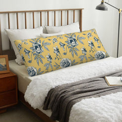 Repeating blue rose mustard body pillow cover styled across a bed
