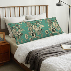 Green toile body pillow cover styled across a bed