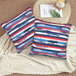 4th of July velvet pillow covers with red, white and blue brushstroke stripes, styled on a woven chair