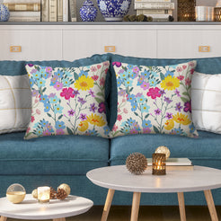 Water-resistant pillow covers with cream pastel wildflower bouquets, styled on a teal sofa