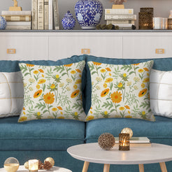 Water-resistant pillow covers with cream orange and yellow meadow flowers, styled on a teal sofa