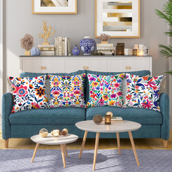 Short-pile plush pillow covers with bold multicolor folk floral patterns on white, styled on a teal sofa