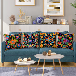 Short-pile plush pillow covers with bright folk floral patterns on black, styled on a teal sofa