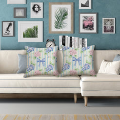 Water-resistant linen-look polyester pillow covers with hydrangeas and blue bows on pale stripes, styled on a white sofa