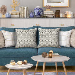 Outdoor water-resistant linen-look polyester pillow covers with black geometric bands on cream, styled on a blue sofa