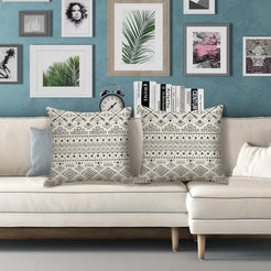 Outdoor water-resistant linen-look polyester pillow covers with black geometric bands on cream, styled on a white sofa