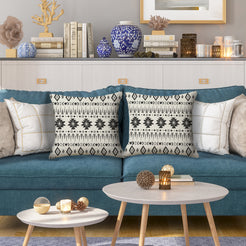 Outdoor water-resistant linen-look polyester pillow covers with gray and black tribal stripes, styled on a blue sofa