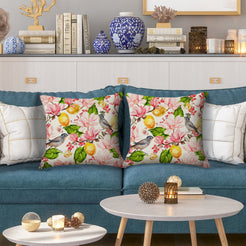Outdoor water-resistant linen-look polyester pillow covers with birds, lemons and pink flowers, styled on a blue sofa