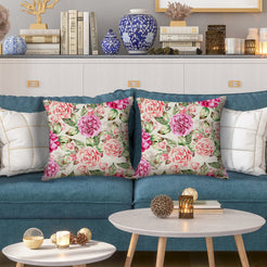 Outdoor water-resistant linen-look polyester pillow covers with bright pink roses, styled on a blue sofa