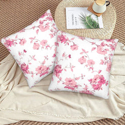 Pink toile velvet pillow covers with pink cherry blossom branches on white, styled on a woven chair
