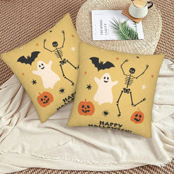 Halloween pillow covers with mustard ghosts, skeletons and pumpkins with a Happy Halloween message, styled on a woven chair