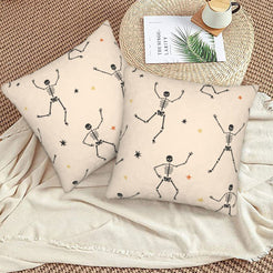 Halloween pillow covers with cream dancing skeletons, styled on a woven chair
