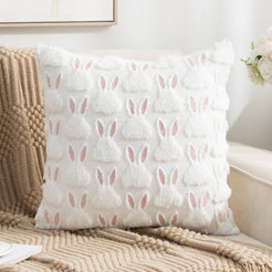 quilted polyester pillow cover with raised white bunny silhouettes and pink ears, styled on a cream chair
