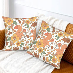 Set of two velvet pillow covers with cream squirrel, acorn and floral pattern, styled on a sofa