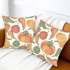 Set of two velvet pillow covers with cream colorful gourds and pumpkins, styled on a sofa